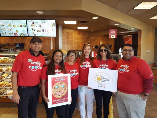 Volunteers participating in the Smile Cookie Campaign holding placards at one of Tim Hortons' store