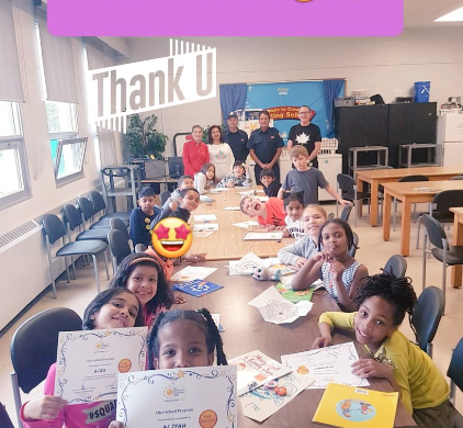 Children holding their certificates in a classroom.