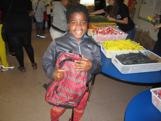 A happy child holding a giveaway backpack