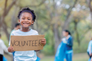 Child holding banner saying Volunteer