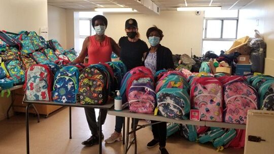 Volunteers at the club with school bags, purchased from generous donations for children