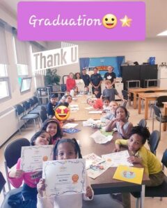 A group of children sitting at a table with graduating certificates.