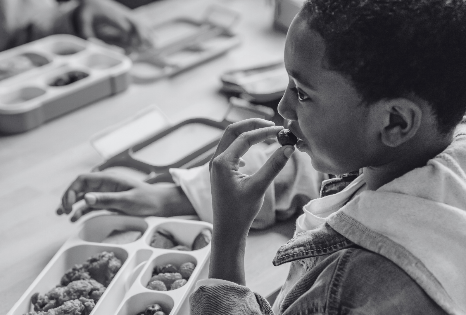 A young child focused on eating a meal from a compartmentalized tray, illustrating a moment of nourishment and daily life.