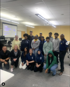 Group of students and instructors posing for a photo in a classroom setting.